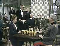 George de Villefort (Ivor Roberts) officiates at the inter-island chess tournament match between Louise Gardner (Jane Wenham) and  Generalmajor Müller (David Waller).